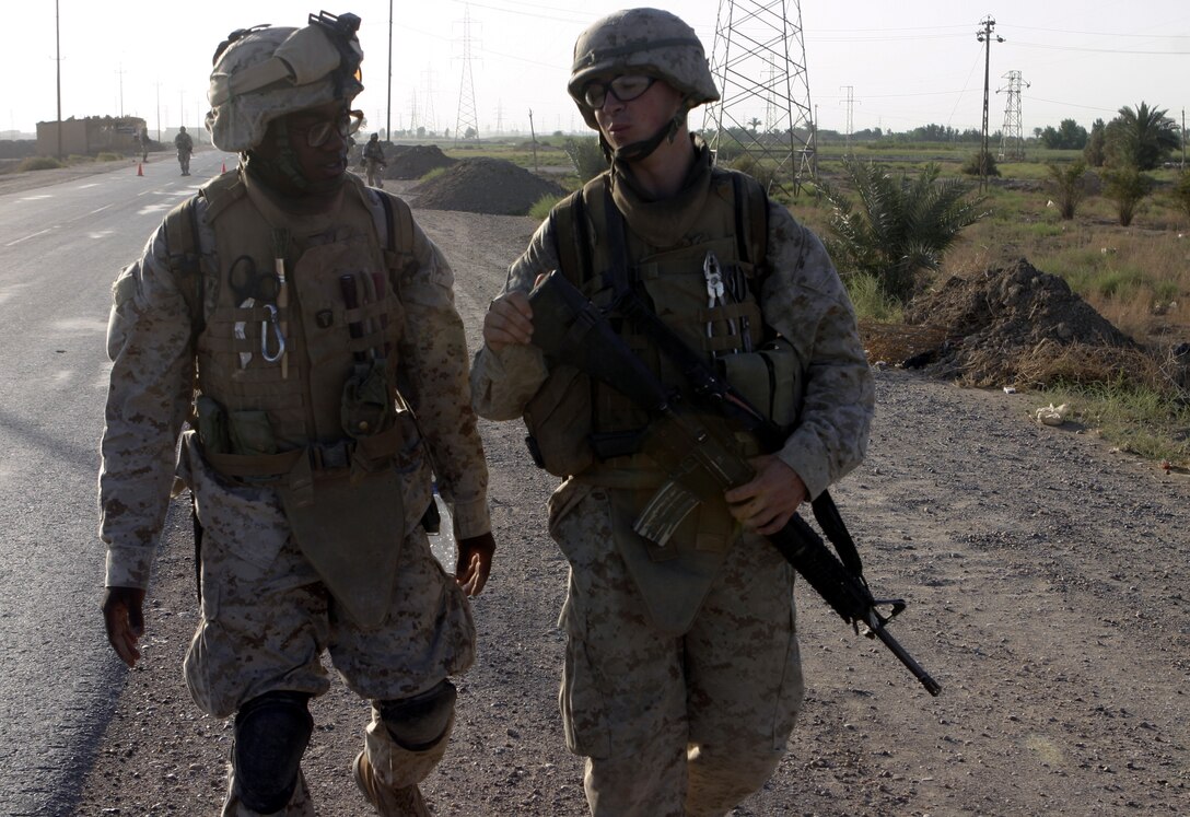 SAQLAWIYAH, Iraq - Seaman Clarence Washington, a corpsman with 4th Platoon, Company A, 1st Battalion, 6th Marine Regiment, left, speaks with a fellow Marine while patrolling the town's streets July 27.  The 26-year-old Caruthersville, Mo. native is one of several 'docs' who live and work alongside the infantrymen here, administering first aid in combat and treating acute illnesses.