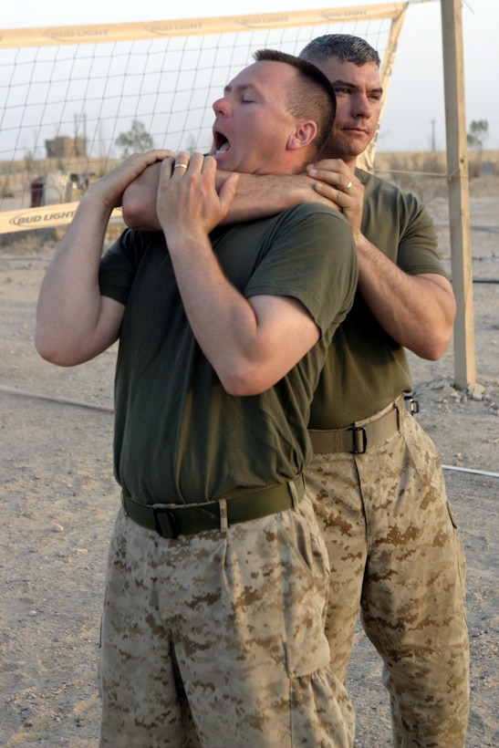 CAMP BAHARIA, Iraq - Chief Petty Officer Nathan Whiddon, 1st Battalion, 6th Marine Regiment's battalion aid station chief, chokes out Petty Officer 1st Class Jeremy Slone, BAS lead petty officer, during a martial arts training session here July 29.  The battalion's corpsman and chaplain received instruction on how to perform self-defense maneuvers such as countering choke holds and various types of strikes.
