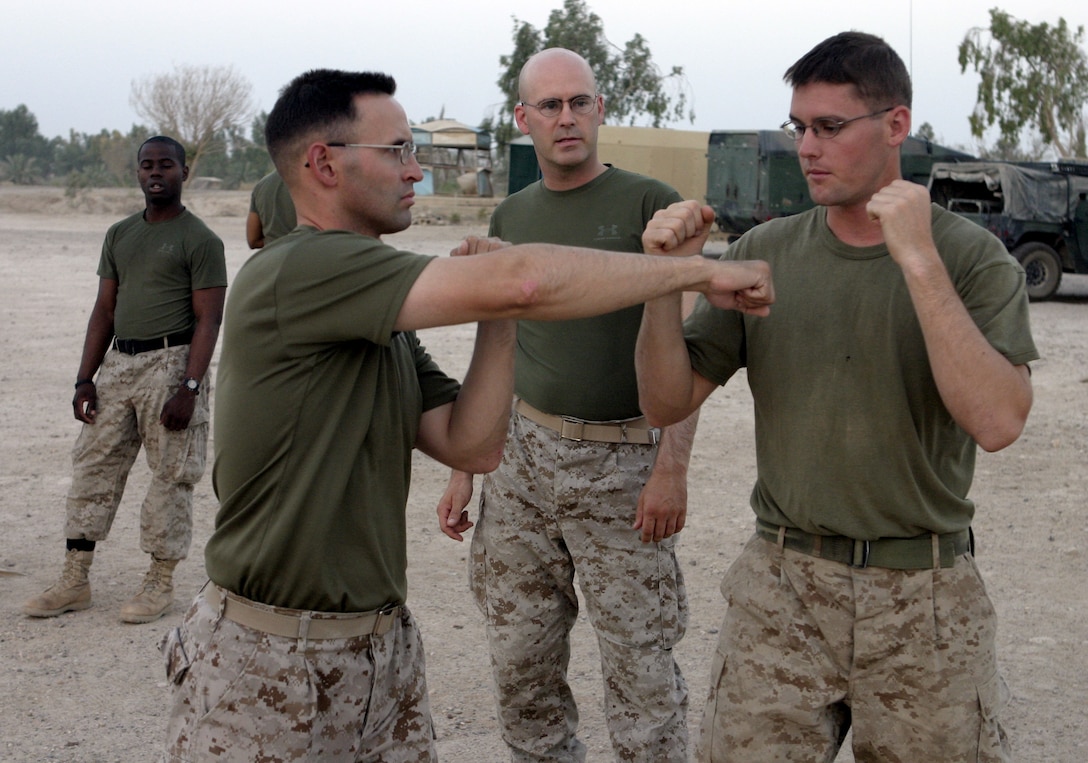 CAMP BAHARIA, Iraq - First Lieutenant Dana Sanford, 1st Battalion, 6th Marine Regiment's motor transport section's assistant officer-in-charge, right, demonstrates proper technique while deflecting Lt. Jared Vogler's punch during a martial arts training session here July 29.  The 24-year-old Sterling, Mass. native is a green belt instructor in the Marine Corps Martial Arts Program, and is currently teaching several Marines and sailors in his unit self-defense.