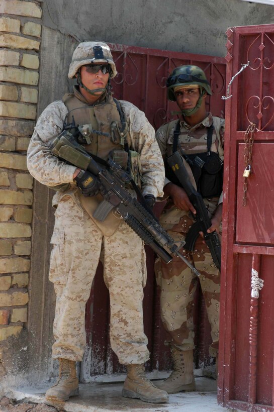 AR RAMADI, Iraq (July 31, 2005) - Corporal Grant R. Birtcher, a rifleman with the Combine Action Platoon, Company B, 1st Battalion, 5th Marine Regiment, and a member of the Iraqi Security Forces keep a vigilant watch for threats from within the courtyard of a residence during a mission in the city here July 31. Birtcher, a 20-year-old half Navajo American Indian from Window Rock, Ariz., leads newly trained members of the ISF on missions in the city to hone their military skills. The 2002 Window Rock High School graduate conducts daily missions in the city with his ISF counterparts. Birtcher and between 12 and 24 ISF accompany Marines with 1st Battalion, 5th Marines. Photo by: Cpl. Tom Sloan