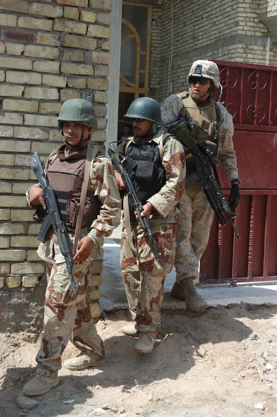 AR RAMADI, Iraq (July 31, 2005) - Corporal Grant R. Birtcher, a rifleman with the Combine Action Platoon, Company B, 1st Battalion, 5th Marine Regiment, and two members of the Iraqi Security Forces exit the courtyard of a residence and take to the streets during a mission in the city here July 31. Birtcher, a 20-year-old half Navajo American Indian from Window Rock, Ariz., leads newly trained members of the ISF on missions in the city to hone their military skills. The 2002 Window Rock High School graduate conducts daily missions in the city with his ISF counterparts. Birtcher and between 12 and 24 ISF accompany Marines with 1st Battalion, 5th Marines. Photo by: Cpl. Tom Sloan