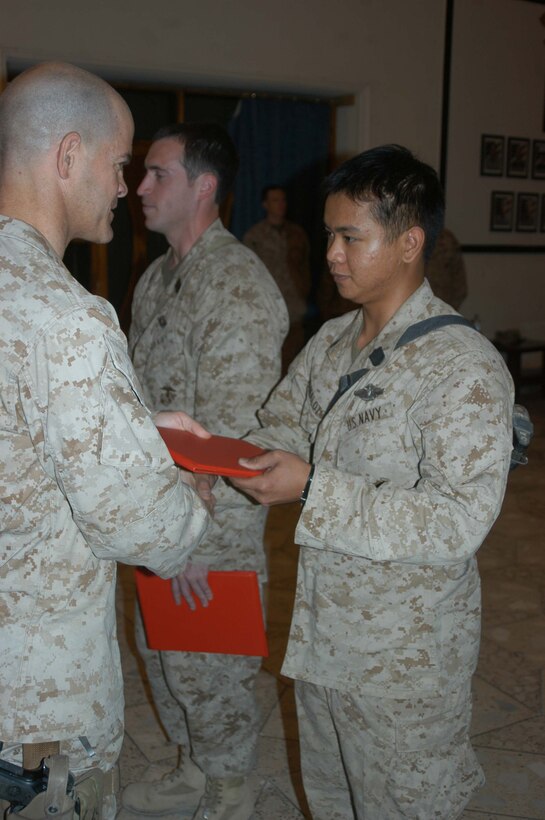 CAMP HURRICANE POINT Ar Ramadi, Iraq (Aug. 2, 2005) - Petty Officer 3rd Class Francis P. Manaloto, a hospitalman with 3rd Platoon, Company W, 1st Battalion, 5th Marine Regiment, receives his award citation for earning his Fleet Marine Force pin from Capt. Michael J. Butler, commanding officer of Company W, during a ceremony here July 24. The 21-year-old Manaloto from Sinjana, Guam used every chance he had to study the FMF books so he could pass the test. When he wasn't on missions in the Al Anbar capital with his Marine comrades, he devoted three hours of his time each day for a month to studying. Earning the FMF pin symbolizes his knowledge of Navy and Marine Corps history, customs and courtesies and Marine Corps and amphibious operations. Manaloto enlisted in the Navy after graduating from John F. Kennedy High School in 2002 so he could see the world and someday attend college. This is his second deployment to Iraq supporting Operation Iraqi Freedom in as many years. Photo by: Cpl. Tom Sloan