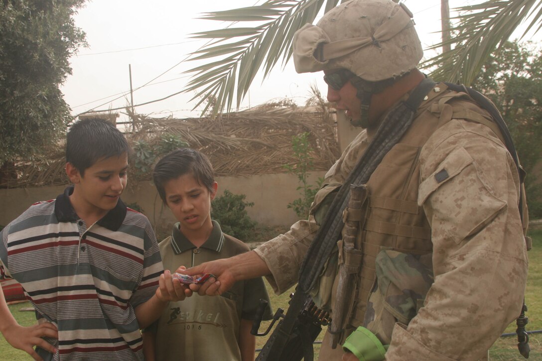 BANI DAHRI, Iraq (July 13, 2005)- Lance Cpl. Raphael P. Ramos, 21, from Carolina, Puerto Rico and a squad automatic weapon gunner with 1st Squad, 3rd Platoon, Company K, 3rd Battalion, 2nd Marine Regiment, Regimental Combat Team-2 takes time during a patrol to make a couple Iraqi children happy with toys during Operation Quick Strike. The 2003 Ana Roque High School graduate is making his first deployment in support of Operation Iraqi Freedom and has decided to continue his career and become a Marine Corps officer. (Official USMC photo by Lance Cpl. Lucian Friel)(RELEASED)