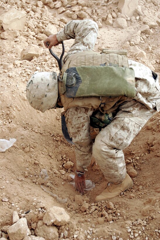 Husaybah, Iraq ( November 7, 2005)--Scouts and combat engineers like 21-year-old Cpl. Joshua D. Jackson from Mt. Vernon, Ind., with 2nd platoon, 1st LAR discover a huge ammunition cache during Operation Steel Curtain. Jackson dug a few feet into the grave after a metal detector signaled possibly metal there. The possible metal turned out to be 118 boxes of ammo. (Official U. S. Marine Corps photo by Corporal Ken Melton)