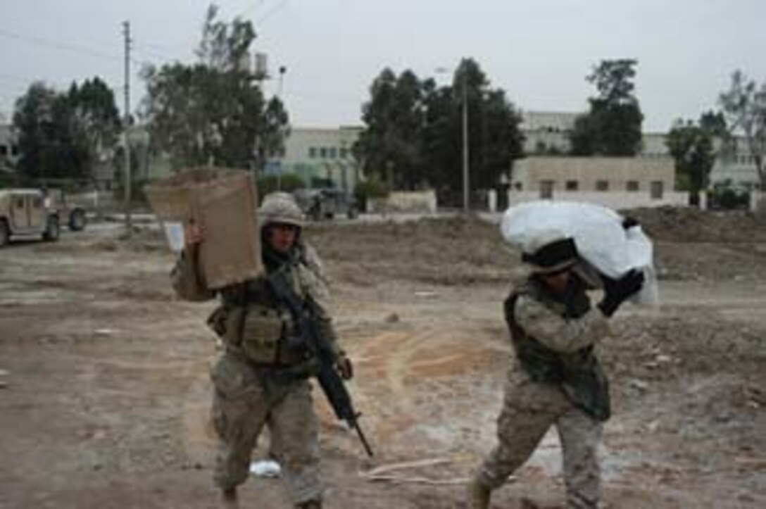 AR RAMADI, IRAQ (March 7,2005) - The 28-year-old noncommissioned officer for 4th Civil Affairs Group, 2nd Battalion, 5th Marine Regiment and New Jersey native, Sgt. John J. Ramirez, and the 24-year-old 4th CAG's translator, Ricky Wissam, carry boxes full of school supplies they plan to deliver to children at the Kahled Bin Waleed intermediate school. Second Battalion, 5th Marine Regiment's 4th Civil Affairs Group visited two schools here with a representative of 1st Battalion, 5th Marine Regiment's 5th CAG, Maj. Benjamin B. Busch, marking the beginning of 1st Battalion's Relief in Place. The purpose of the visits was to conduct a visual verification of repairs rendered. The team leader for 1st Battalion's 5th CAG, Maj. Benjamin B. Busch, accompanied 4th CAG in an effort to gain knowledge on how to conduct future missions of his own when 2nd Battalion leaves.    (Official United States Marine Corps photo by Cpl. Tom Sloan)