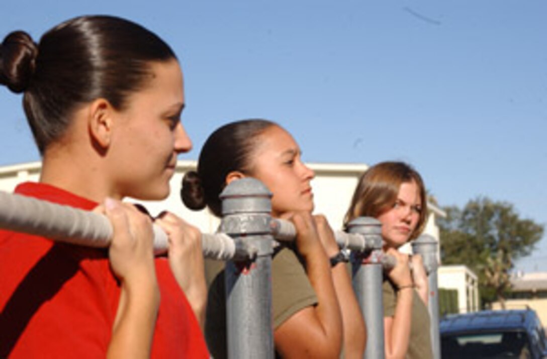 Sgt. Holly Askins, Pvt. Azucena Ledesma and Pfc. Marissa Keeter, Marine Communications-Electronics School, A Company, suffer together through the Flex-Arm Hang competition at the MCCES field games.