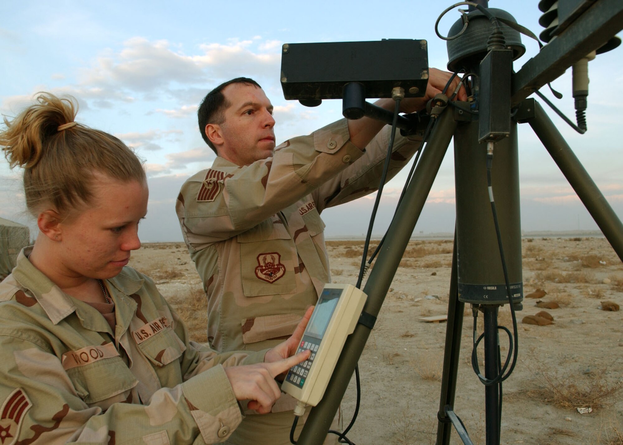 BAGRAM AIR BASE, Afghanistan -- Senior Airman Laci Wood collects weather data from a weather observation system while Tech. Sgt. Carlton Hatfield readjusts the system's transmitter.  It is one of several methods the 455th Air Expeditionary Wing's combat weather team here uses to gather detailed weather updates hourly for pilots and Combined Joint Task Force 76 operations planners.   Airman Wood is deployed from Eglin Air Force Base, Fla., and Sergeant Hatfield is from Shaw AFB, S.C.  (U.S. photo by Staff Sgt. Jennifer Lindsey)