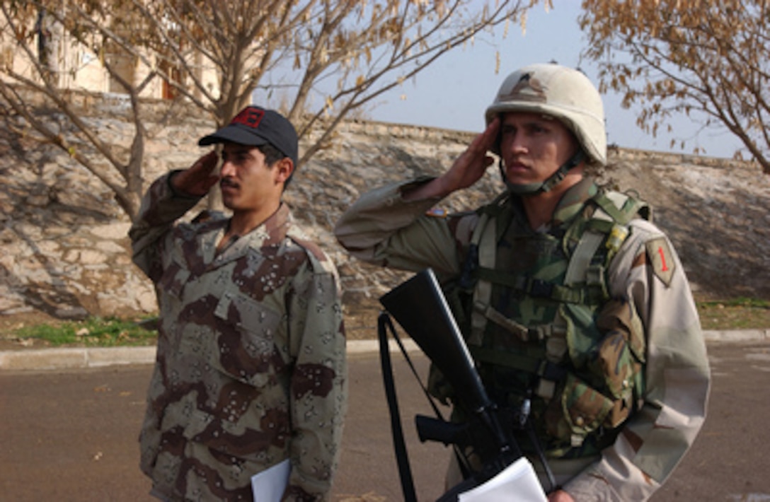 An Iraqi and U.S. soldier stand side-by-side as they render salutes during the playing of the Iraqi National Anthem at the ceremony of the Iraqi Army Day in Tikrit, Iraq, on Jan. 6, 2005. The 4th Iraqi National Guard Division with its headquarters in Tikrit, Iraq, is being activated into the new Iraqi Army on one of its training bases, collocated with the U.S. Army's 1st Infantry Division. One of the first missions of the new Iraqi Division will be to gradually assume the security of the city of Tikrit. 