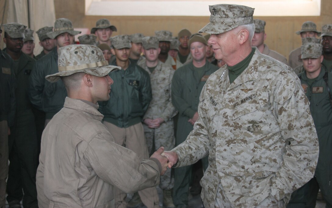 Lieutenant Gen. John W. Bergman, the commander of Marine Forces Reserve, hands Cpl. Jason Mauro, an aerial gunner and observer with HMM-774 and a Virginia Beach, Va., native, a challenge coin at Al Asad, Iraq, Dec. 7.  ?It?s nice to know our hard work, sweat and blood get recognized and appreciated by a man of his magnitude,? said Mauro. ?I like to believe I accepted his coin for the entire unit?s achievements and not just my own.?