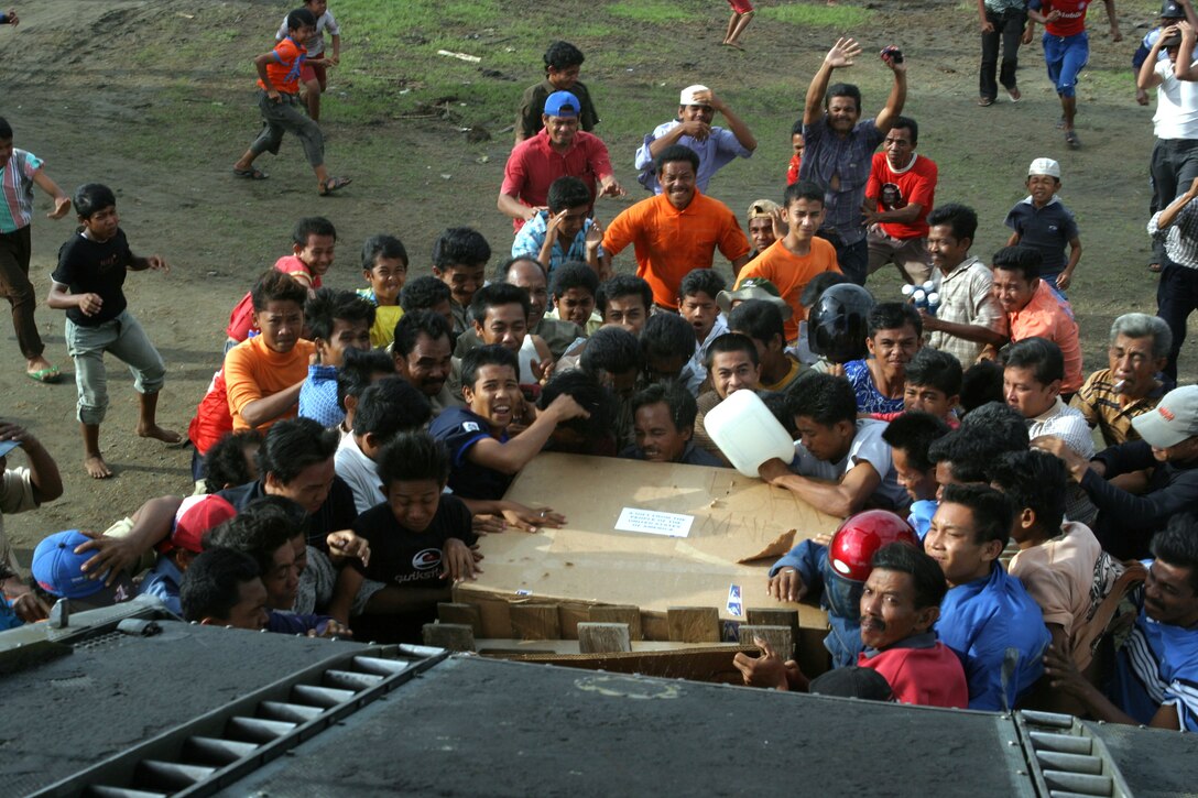 Local civilians in need of food and water swarm a pallet of noodles as its dropped from the back of a CH-46E Sea Knight helicopter as part of the humanitarian effort provided by 15th Marine Expeditionary Unit (Special Operations Capable) and USS Bonhomme Richard. Marines and Sailors of the ship and the MEU are in Indonesia to provide food, supplies, and humanitarian aid to for thousands of those affected by the natural disaster.