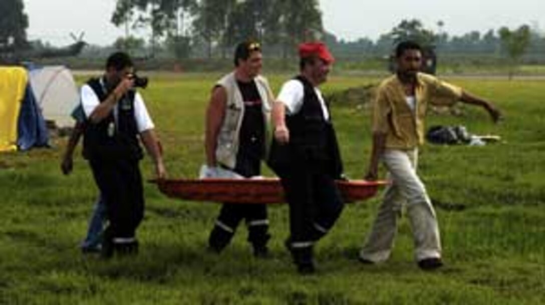 Aid workers carry a wounded Indonesia citizen to a medical tent during recovery efforts here. Marines from the 15th Marine Expeditionary Unit (Special Operations Capable) and 3rd Marine Division have been assisting relief efforts since shortly after the disaster.