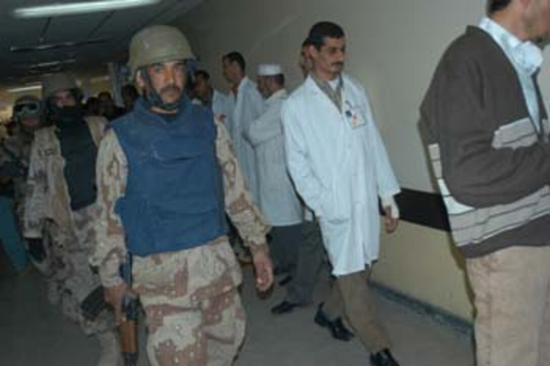 AR, RAMADI, Iraq (March 8, 2005) - Iraqi Security Force commandos walk down a hallway in the Ar Ramadi General Hospital here while doctors and other hospital staff stand and lean against the walls. More than 20 ISF Commandos operated alongside Marines with Company A, 1st Battalion, 5th Marines when the joined Company G, 2nd Battalion 5th Marines in a raid on the hospital in search of weapons caches, insurgents and crimes against humanity. First Battalion, 5th Marines' Human Exploitation Team, Information Operations and the 4th and 5th Civil Affairs Groups also participated in the mission, which lasted more than four hours. . (Official United States Marine Corps photo by Cpl. Tom Sloan)