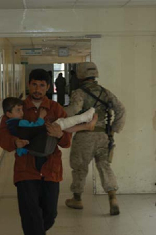 AR, RAMADI, Iraq (March 8, 2005) - An Iraqi man carries his son, who has a broken leg, down a hall in the Ar Ramadi General Hospital here. A Marine walks the opposite direction. Marines with Company A, 1st Battalion, 5th Marines joined Company G, 2nd Battalion, 5th Marines in a raid on the hospital in search of weapons caches, insurgents and crimes against humanity. First Battalion, 5th Marines' Human Exploitation Team, Information Operations, the 4th and 5th Civil Affairs Groups and more than 20 Iraqi Security Force Commandos also participated in the mission, which lasted more than four hours.  (Official United States Marine Corps photo by Cpl. Tom Sloan)