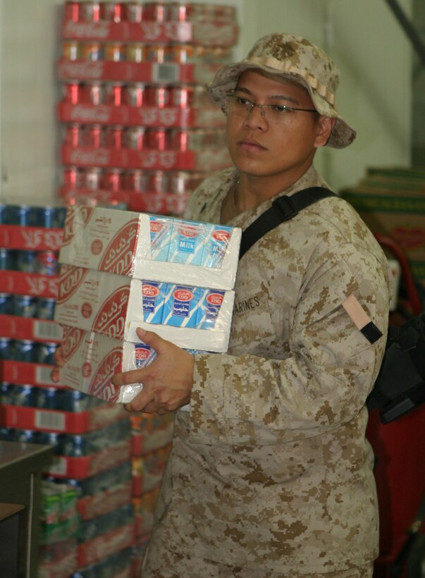 Corporal Ryan Amador, a 22-year-old food services specialist with Headquarters Battalion, 2d Marine Division, restocks milk in between meals at the mess hall, March 8, 2005.  Amador's unit recently deployed here for stability and security operations as part of the Global War on Terrorism.  U.S. Marine Corps photo by Sgt. Stephen D'Alessio (RELEASED)