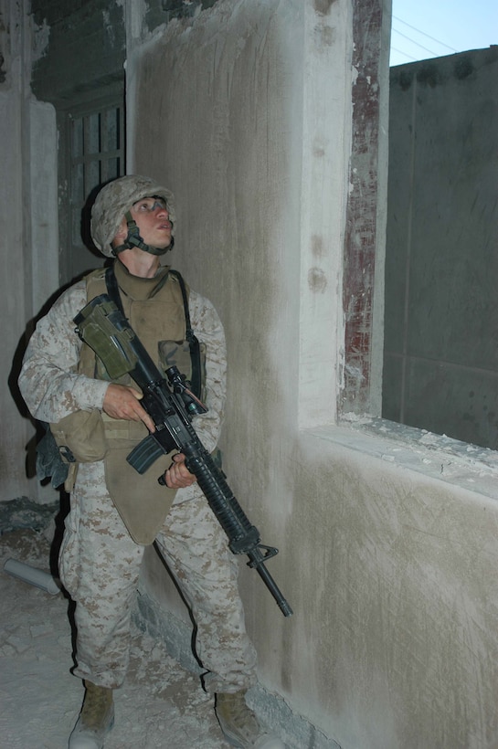 AR RAMADI, Iraq (April 8, 2005) - Twenty-five-year-old Conrad J. Larsen, a rifleman with 1st Squad, 4th Platoon, Company A, 1st Battalion, 5th Marine Regiment, keeps a vigilant watch from a window of an abandoned building he and his Marines used for an over watch during a patrol of the of the marketplace here. The Salt Lake City native and other warriors with 4th Platoon, Company A, 1st Battalion, 5th Marines, patrolled the marketplace in an effort to familiarize themselves with their area of operations and determine how the local Iraqis feel about their presence in the area. The Marines also handed out positive and anti-insurgent propaganda to the Iraqis and searched for insurgents and things out of the ordinary during the two-hour operation. Photo by Cpl. Tom Sloan