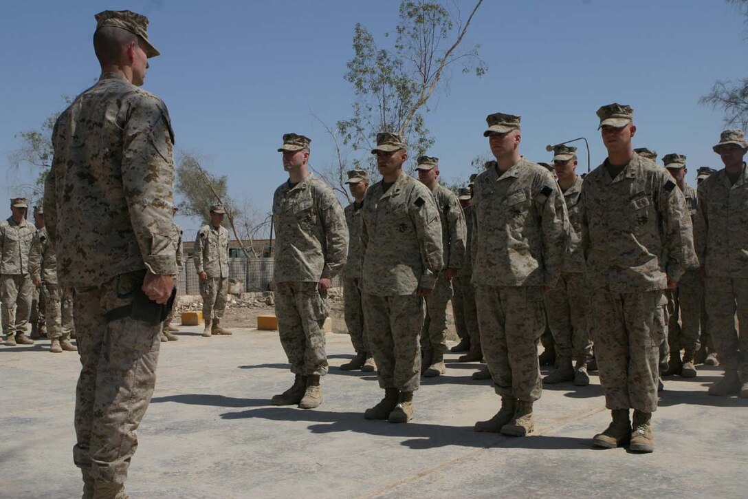 CAMP FALLUJAH, IRAQ -- Lined up in front of the formation, Capt. William G. Rayne, Sgt. Jorge H. Herrera, Lance Cpl. Joshua C. Landis and Lance Cpl. Curt L. Smith stand at attention as the warrant for the awards are read.  Their fellow Marines in their platoon as well as other various members of the battalion accompanied the Marines.  Official U.S. Marine Corps photo by Lance Cpl. Athanasios L. Genos