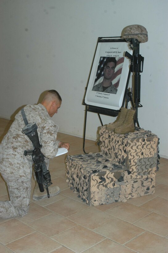CAMP RAMADI Ar Ramadi, Iraq (June 7, 2005) - Corporal Donald W. Ball, a team leader and rifleman with 3rd Squad, Weapons Platoon, Company B, 1st Battalion, 5th Marine Regiment, kneels at the foot of Cpl. Jeff B. Starr's monument during a memorial ceremony here for the fallen Company B warrior. Starr was killed May 30, Memorial Day, by small arms fire while conducting operations against enemy forces in this city. Starr was a 22-year-old native of Snohomish, Wash. Ball, a 22-year-old from Salt Lake City, who served alongside Starr during three deployments in support of Operation Iraqi Freedom, gave a eulogy during the ceremony. Photo by: Cpl. Tom Sloan