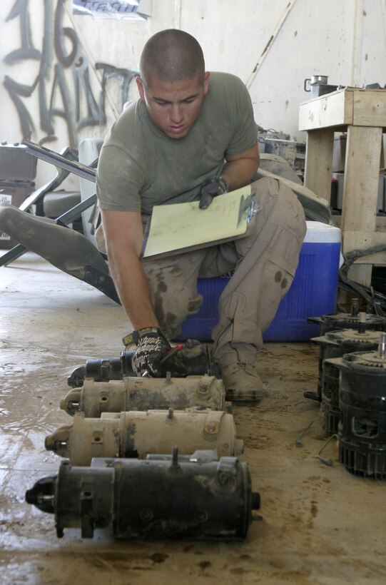 CAMP BAHARIA, Iraq - Lance Cpl. Joshua Sanchez, a maintenance management specialist with 1st Battalion, 6th Marine Regiment's motor transport section, jots down the serial numbers off some starters here June 8.  The battalion's Motor 'T' Marines service several military trucks' engines, transmissions and electric systems, along with freighting fuel and water to locations throughout the camp and Fallujah.
