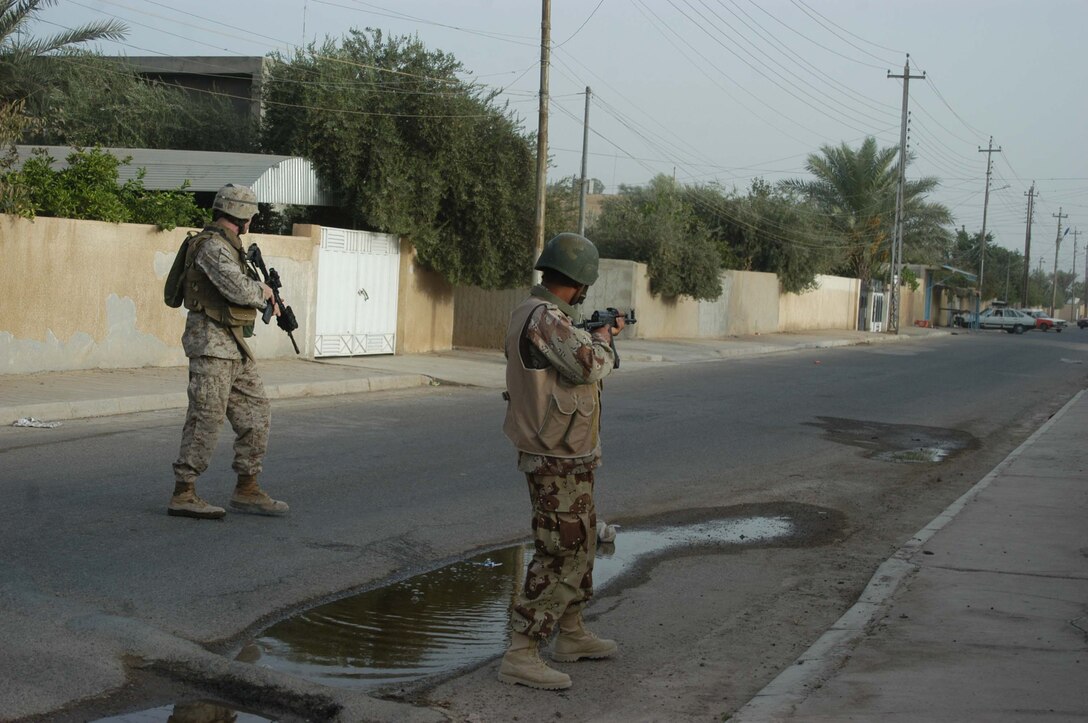 AR RAMADI, Iraq (Aug. 8, 2005) -Second Lieutenant Michael L. Burke, platoon commander, Combined Action Platoon(CAP), Company B, 1st Battalion, 5th Marine Regiment, and a member of the Iraqi Security Forces aim in on a vehicle driving toward their position during a foot patrol in the city here Aug. 8. The vehicle stopped, turned around and headed in the other direction. Twenty-seven-year-old Burke from Foxboro, Mass., and his Marines support Operation Iraqi Freedom by training new members of the ISF and employing them on Ramadi's urban battlefield to help secure the city from terrorism. The Marines are letting the ISF carry more of the operational workload because their tactics are improving. Iraqi Security Forces are even leading their own foot patrols. Photo by: Cpl. Tom Sloan