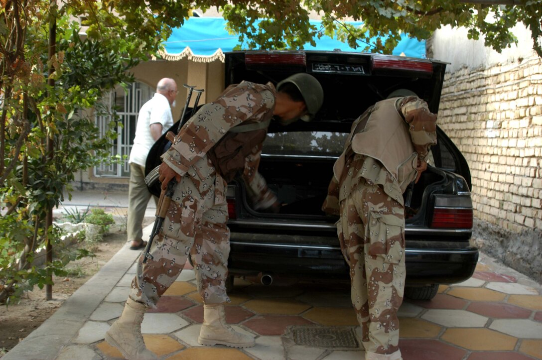 AR RAMADI, Iraq (Aug. 8, 2005) -Two members of the Iraqi Security Forces search a car in an Iraqi man's driveway during a mission in the city here Aug. 8. Many of the Al Anbar capital's locals respond well to having ISF patrol through their neighborhoods conducting security and stabilization operations. Marines with the Combined Action Platoon(CAP), Company B, 1st Battalion, 5th Marine Regiment, support Operation Iraqi Freedom by training new members of the ISF and employing them on Ramadi's urban battlefield to help secure the city from terrorism. The Marines are letting the ISF carry more of the operational workload because their tactics are improving. Iraqi Security Forces are even leading their own foot patrols. Photo by: Cpl. Tom Sloan