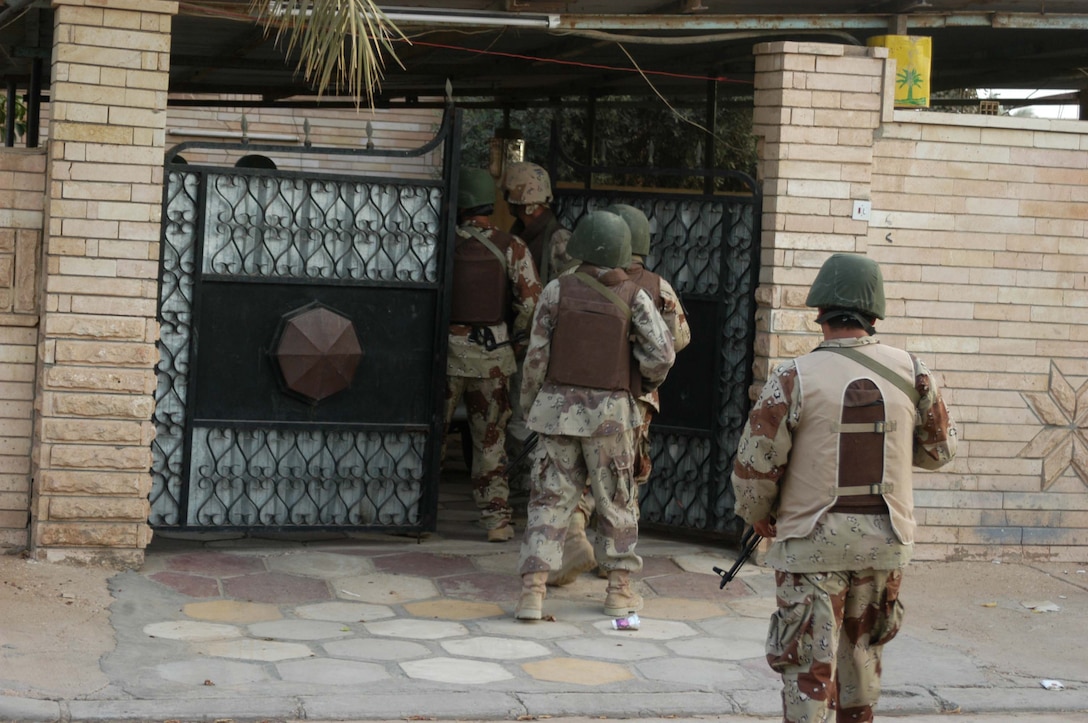 AR RAMADI, Iraq (Aug. 8, 2005) -A squad of the Iraqi Security Forces rush through the entrance of a residence during a mission in the city here Aug. 8. Many of the Al Anbar capital's locals respond well to having ISF patrol through their neighborhoods conducting security and stabilization operations. Marines with the Combined Action Platoon(CAP), Company B, 1st Battalion, 5th Marine Regiment, support Operation Iraqi Freedom by training new members of the ISF and employing them on Ramadi's urban battlefield to help secure the city from terrorism. The Marines are letting the ISF carry more of the operational workload because their tactics are improving. Iraqi Security Forces are even leading their own foot patrols. Photo by: Cpl. Tom Sloan