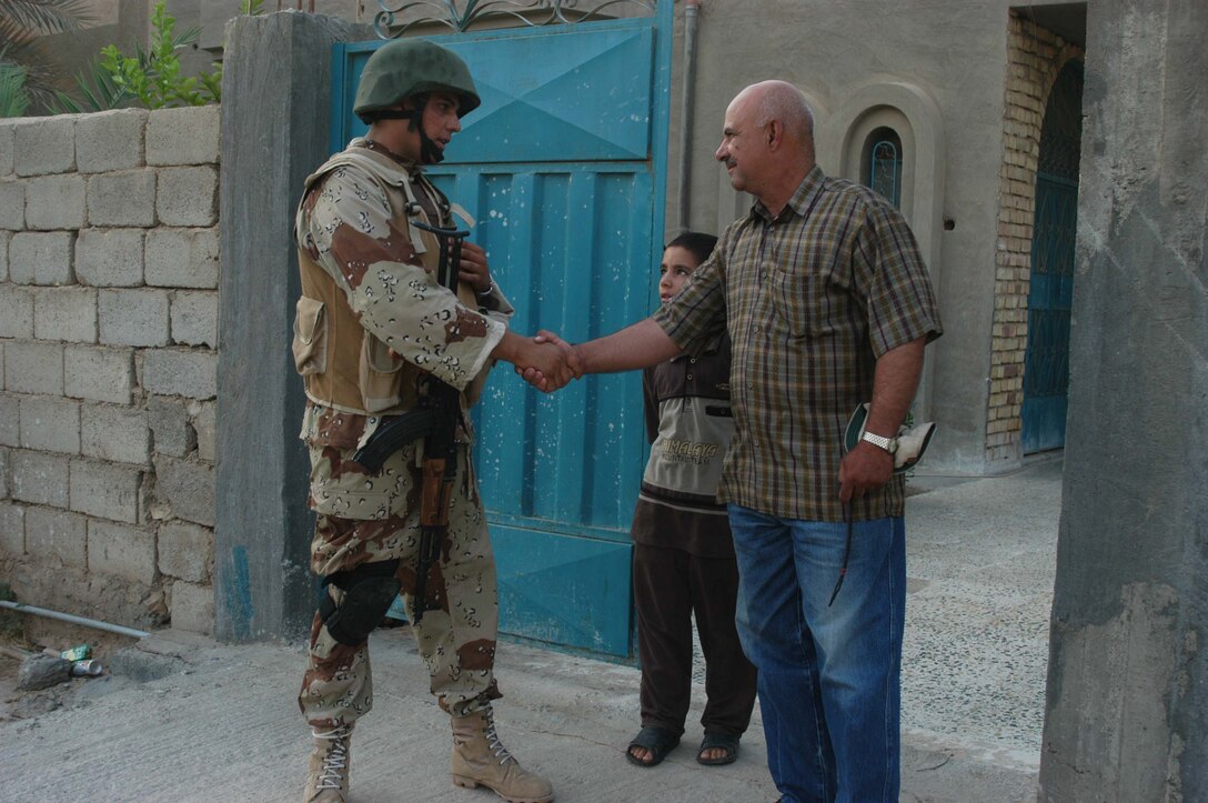 AR RAMADI, Iraq (Aug. 8, 2005) -A member of the Iraqi Security Forces and an Iraqi man shake hands during a mission in the city here Aug. 8. Many of the Al Anbar capital's locals respond well to having ISF patrol through their neighborhoods conducting security and stabilization operations. Marines with the Combined Action Platoon(CAP), Company B, 1st Battalion, 5th Marine Regiment, support Operation Iraqi Freedom by training new members of the ISF and employing them on Ramadi's urban battlefield to help secure the city from terrorism. The Marines are letting the ISF carry more of the operational workload because their tactics are improving. Iraqi Security Forces are even leading their own foot patrols. Photo by: Cpl. Tom Sloan