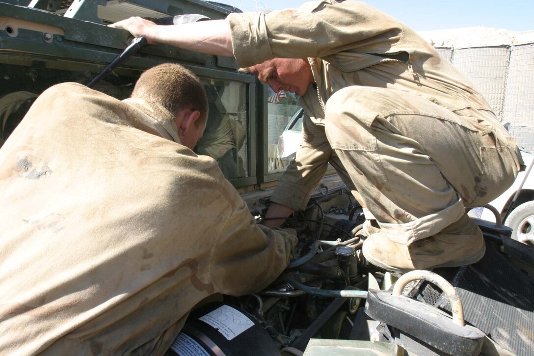 HADITHA DAM, Iraq (Oct. 22, 2005)  - (left to right) Orland, Calif. native Cpl. Joshua E. Thompson and Claremore, Okla. native Cpl. Timothy R. Roundtree, both mechanics for 3rd Battalion, 1st Marine Regiment, work on a Humvee here Oct. 22.  Now on their second deployment together, these two Marines have been together in every unit since joining the Marine Corps at the same time. (Official Marine Corps photo by Cpl. Adam C. Schnell)