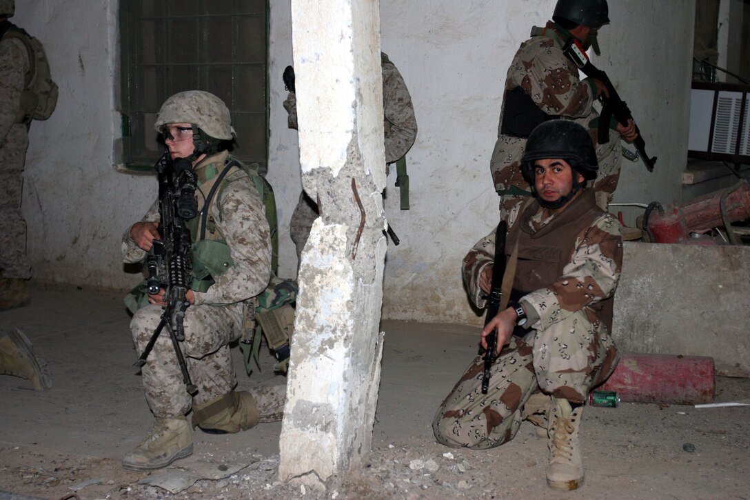 AR RAMADI, Iraq (December 8, 2005) - A Marine with Company I, 3rd Battalion, 7th Marine Regiment and an Iraqi soldier post guard outside a building while their counterparts search it for illegal weapons caches during Operation Skinner Dec. 8. Photo by Cpl. Shane Suzuki