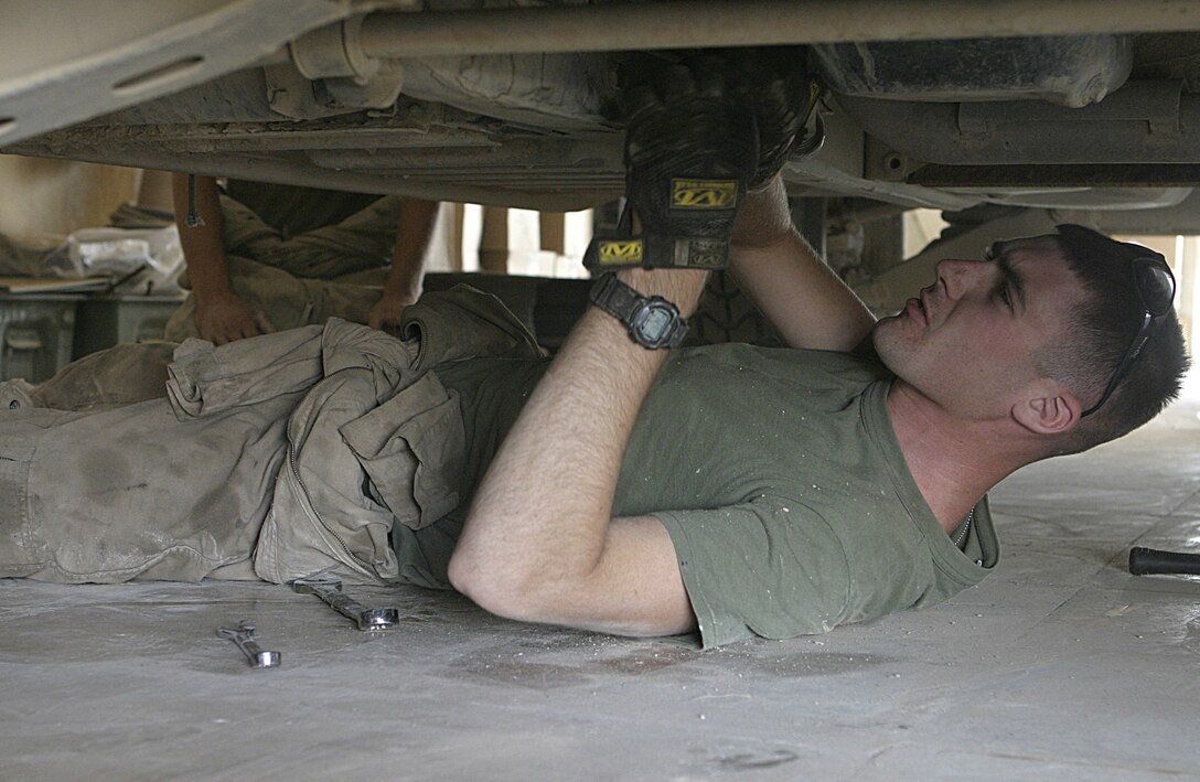 CAMP BAHARIA, Iraq - Cpl. Michael Morgan, a vehicle mechanic with 2nd Platoon, Truck Company, Headquarters Battalion, 3rd Marine Division, works underneath a High Mobility Multi-Wheeled Vehicle inside the maintenance bay here.  The Truck Company vehicle mechanics and operators, originally from Okinawa, have been working alongside 1st Battalion, 6th Marine Regiment personnel in and around Fallujah since mid-March, accomplishing tasks such as servicing vehicles, conducting supply and logistics convoys, and transporting the infantrymen around the city.