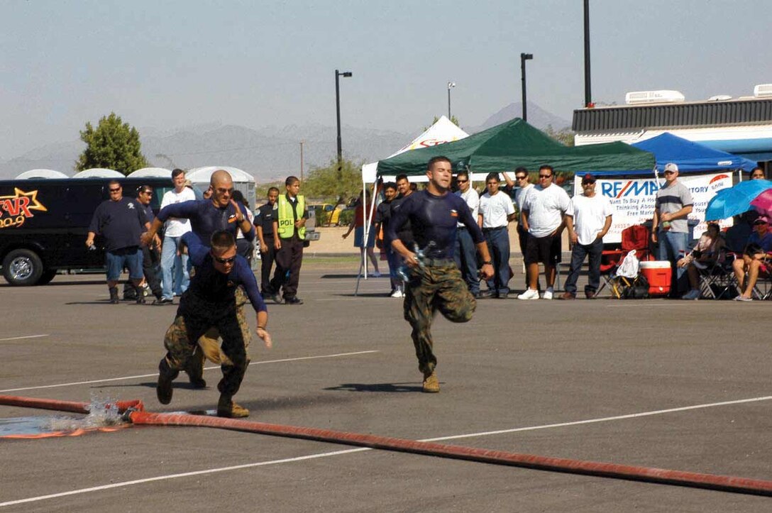 Cpl. Matthew S. Weiland, Lance Cpl. Edward L. Asher and Sgt. Ryan M. Pratt, all Aircraft Rescue Fire Fighting Marines, sprint to the finish line during the Make and Break event of the Somerton/Cocopah Fire Department 2005 Fire Muster at the Cocopah Casino?s recreational vehicle parking lot Oct. 8. The two ARFF teams entered this competition with victory in mind. The blue team fell short of victory, taking second place to the ARFF green team.