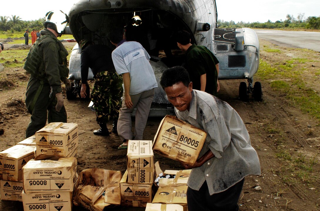 BLANG PIDIE, Indonesia (Jan. 9, 2005) -- Residents here gather bottled water from crew chiefs and pilots on a CH-46E Sea Knight helicopter as they deliver it to the affected areas of the country.  The 15th Marine Expeditionary Unit (Special Operations Capable) has been providing desperately needed humanitarian aid to cities and villages along more than 150 miles of Sumatra's western coastline.  (Photo by Gunnery Sgt. Robert Knoll)
