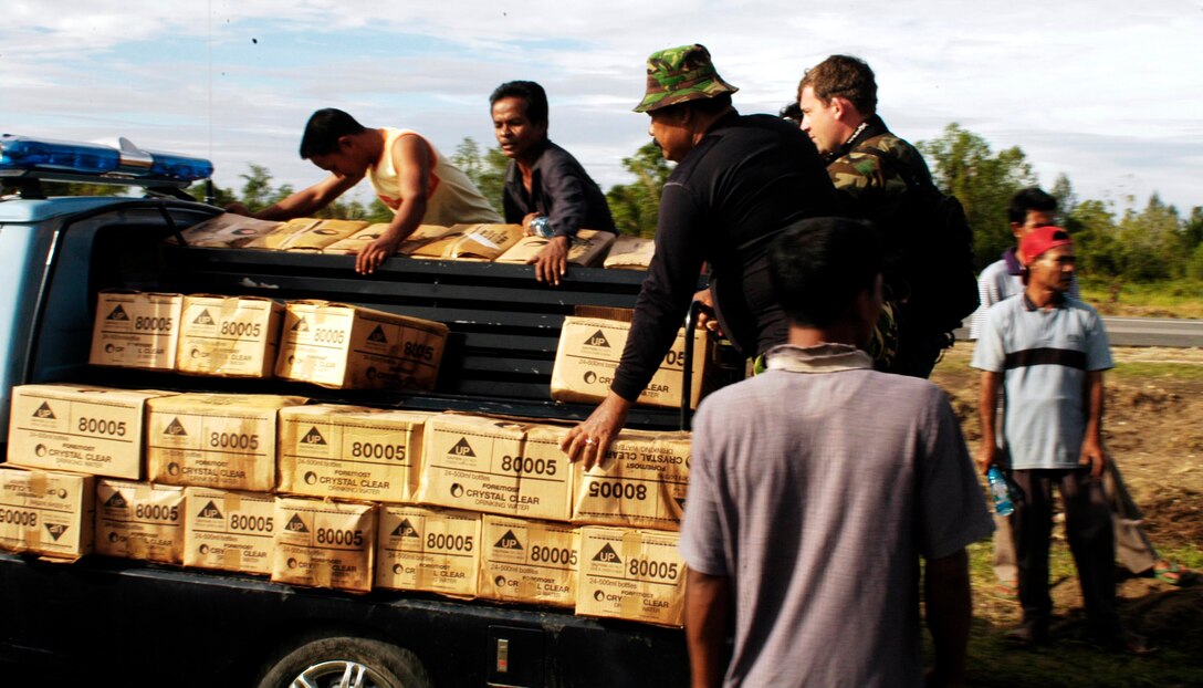 BLANG PIDIE, Indonesia (Jan. 9, 2005) -- Piled on the back of a pick-up truck, local volunteers ride with water they just received from Marines aboard a CH-46E Sea Knight helicopter. The 15th Marine Expeditionary Unit (Special Operations Capable) has been providing desperately needed humanitarian aid to cities and villages along more than 150 miles of Sumatra's western coastline.  (Photo by Gunnery Sgt. Robert Knoll)