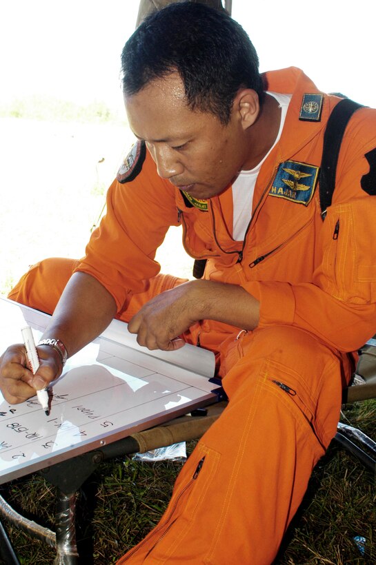 BLANG PIDIE, Indonesia (Jan. 9, 2005) -- Indonesian commercial pilot Mahendra Hajar, 33, makes annotations on a flight-status board while waiting for fuel from the 15th Marine Expeditionary Unit (Special Operations Capable). The 15th MEU (SOC) has been providing desperately needed humanitarian aid to cities and villages along more than 150 miles of Sumatra's western coastline.  (Photo by Gunnery Sgt. Robert Knoll)