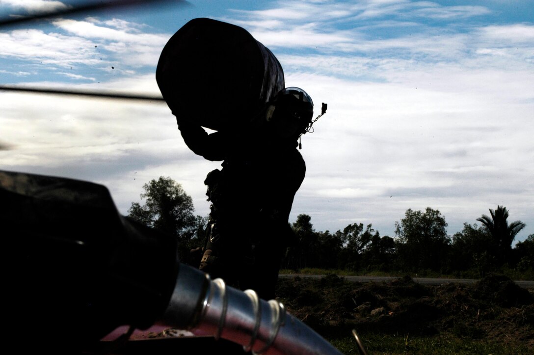 BLANG PIDIE, Indonesia (Jan. 9, 2005) -- Sgt. Chris Garrison, a CH-53E Super Stallion crew chief, carries a 55-gallon drum to fill it with JP-8 aviation fuel. The crew pumped more than 1,100 gallons of humanitarian fuel here to help get a fleet of Indonesian helicopters back in the air to support the relief efforts. The 15th Marine Expeditionary Unit has been providing desperately needed humanitarian aid to cities and villages along more than 150 miles of Sumatra's western coastline.  (Photo by Gunnery Sgt. Robert Knoll)