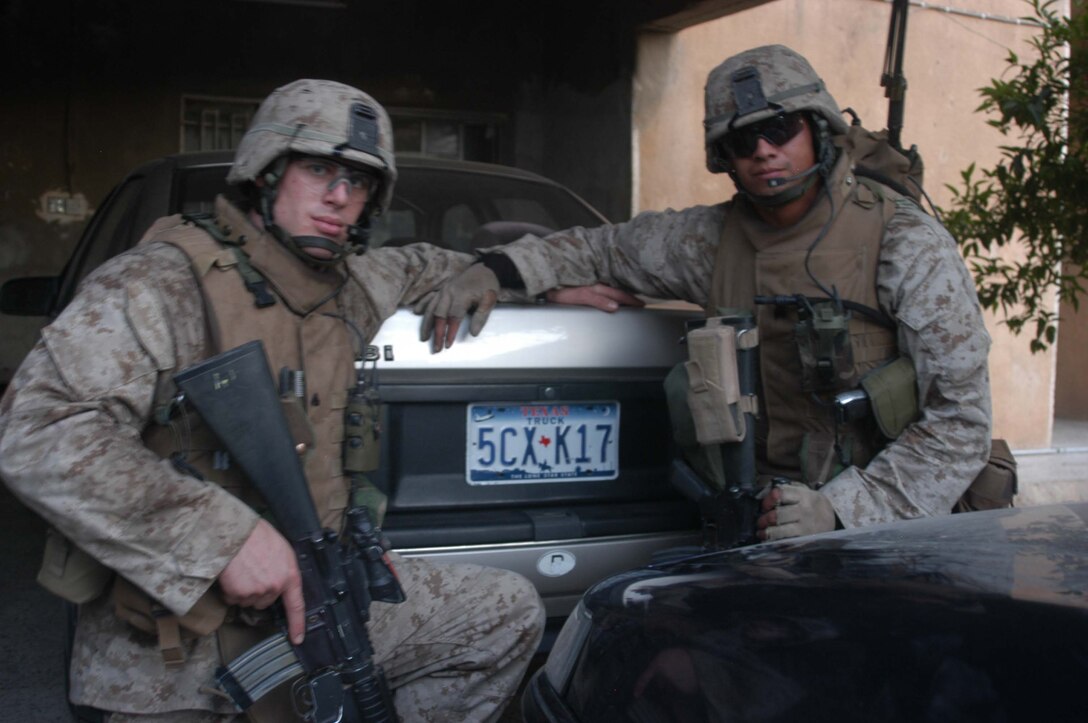 AR RAMADI, Iraq (May 9, 2005) - Corporal Tyler S. Trovillion,(left) a grenadier and team leader with 3rd Squad, 2nd Platoon, Company A, 1st Battalion, 5th Marine Regiment, and 2nd Platoon's platoon sergeant, Sgt. Fidel A. Alcoces, have their picture taken with a vehicle that's mounted with Texas Truck license plates. Marines with rd Squad made the discovery while conducting a presence patrol through the city here. The find served as a reminded of home for 23-year-old Trovillion from Richardson, Texas and 29-year-old Alcoces from San Antonio, Texas. Photo by Cpl. Tom Sloan