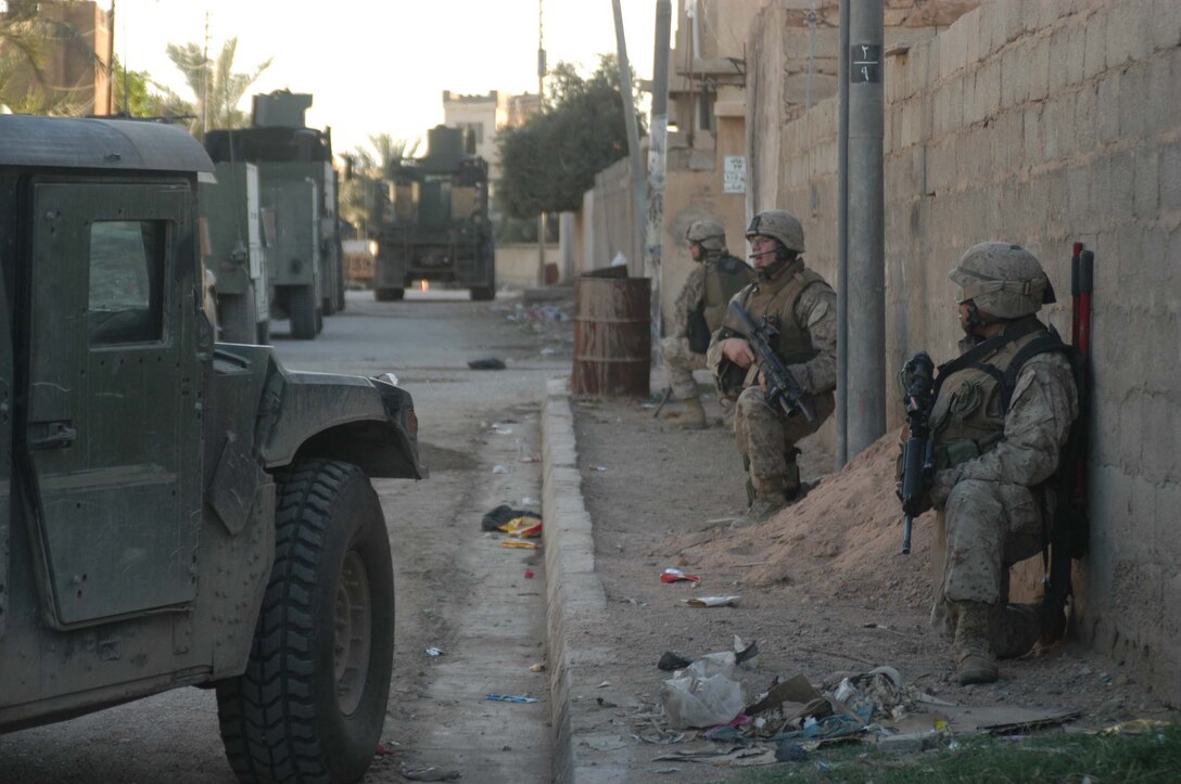 AR RAMADI, Iraq (May 9, 2005) - Twenty-one-year-old Houston native Pvt. Ricardo A. Orega,(front) a rifleman with 3rd Squad, 2nd Platoon, Company A, 1st Battalion, 5th Marine Regiment, takes a knee along a city street here with his fellow squad members, Cpl. Tyler S. Trovillion,(center) a grenadier, team leader and 23-year-old native of Richardson, Texas, and Lance Cpl. Jose A. Gonzalez, a rifleman and 21-year-old from Lake Jackson, Texas. The three Texas natives and other Marines with 3rd Squad, 2nd Platoon, Company A, 1st Battalion, 5th Marines, conducted a presence patrol through a neighborhood and discovered a vehicle that was mount with Texas Truck license plates. Marines with 3rd Squad are the self-proclaimed masters of finding hidden, insurgent material. Photo by Cpl. Tom Sloan