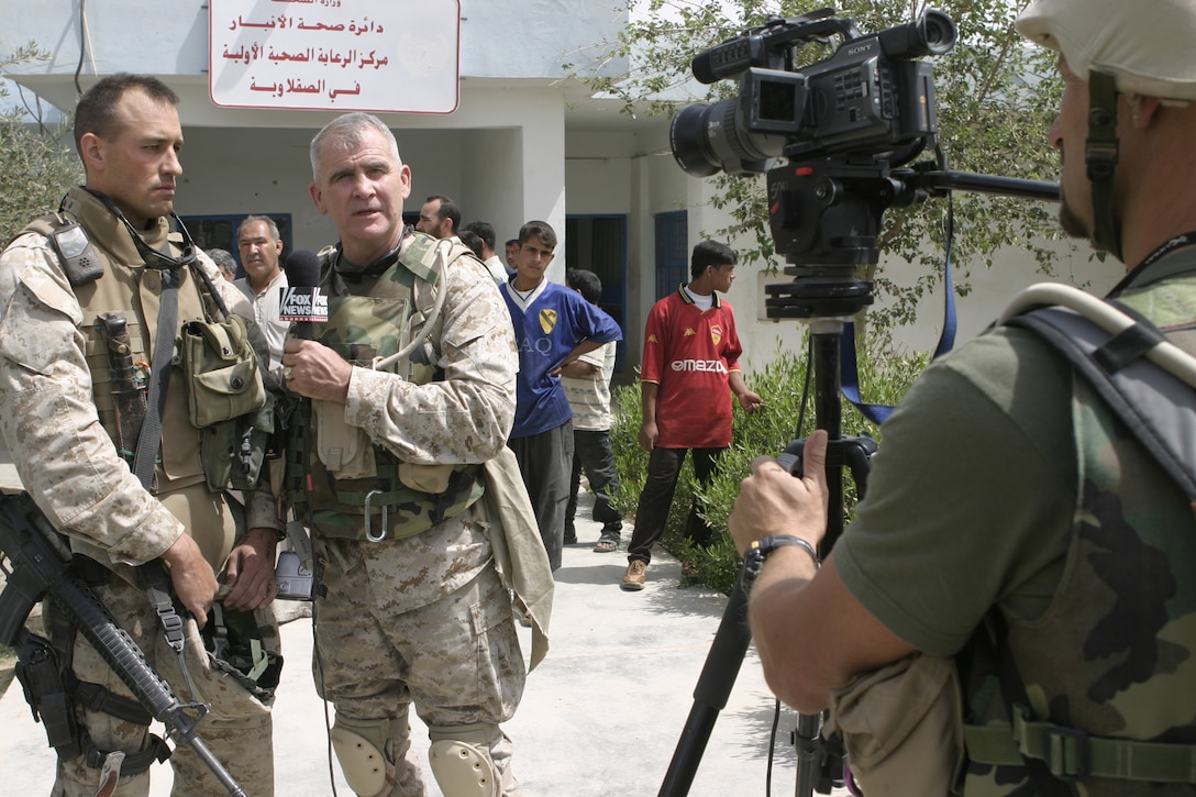 SAQLAWIYAH, Iraq - Oliver North, right, interviews Maj. Chris E. Phelps, team leader for 1st Battalion, 6th Marine Regiment's civil affairs group, left, during his visit to the medical clinic here May 9.  Marines like Phelps traveled with Oliver North throughout the city, showing him the progress the Iraqi soldiers and Marines here have made restoring the city's infrastructure.