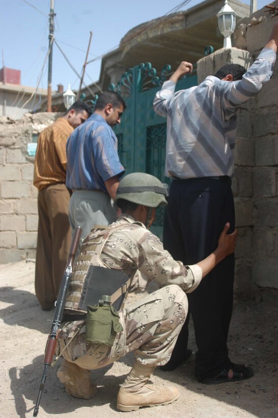 AR RAMADI, Iraq (May 19, 2005) -A member of the Iraqi Security searches a group of Iraqi men during a mission here with Marines of 1st Platoon, Company C, 1st Battalion, 5th Marine Regiment. Marines with 1st Platoon and 15 ISF members conducted five-hour patrol through a portion of the city that has a history of insurgent activity. Two mosques are located in the area. Marines have found insurgent propaganda posted on the outside walls of the holy buildings during past missions. The purpose of this mission was to seek out members of the mujahedeen and fighters from other Middle Eastern countries. The Marines and ISF executed their mission without incident. They searched several house and questioned scores of locals. They searched several house and questioned scores of locals. No insurgents were found. Photo by: Cpl. Tom Sloan