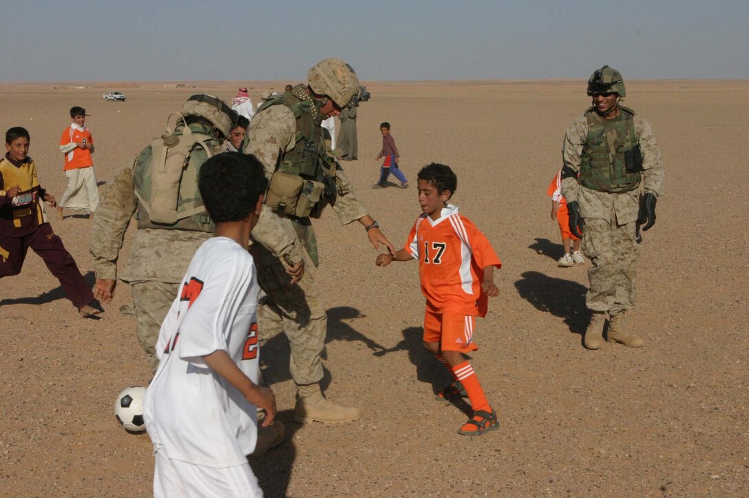 Marines from 2d Light Armored Reconnaissance Battalion and 5th Civil Affairs Group and soldiers from Camp Korean Village put nets on abandoned soccer goals and have a friendly game with the local children. The Marines and soldiers handed out toys, soccer balls and hygiene items to the kids after the game (Photo by LCpl. Zachary W. Lester)