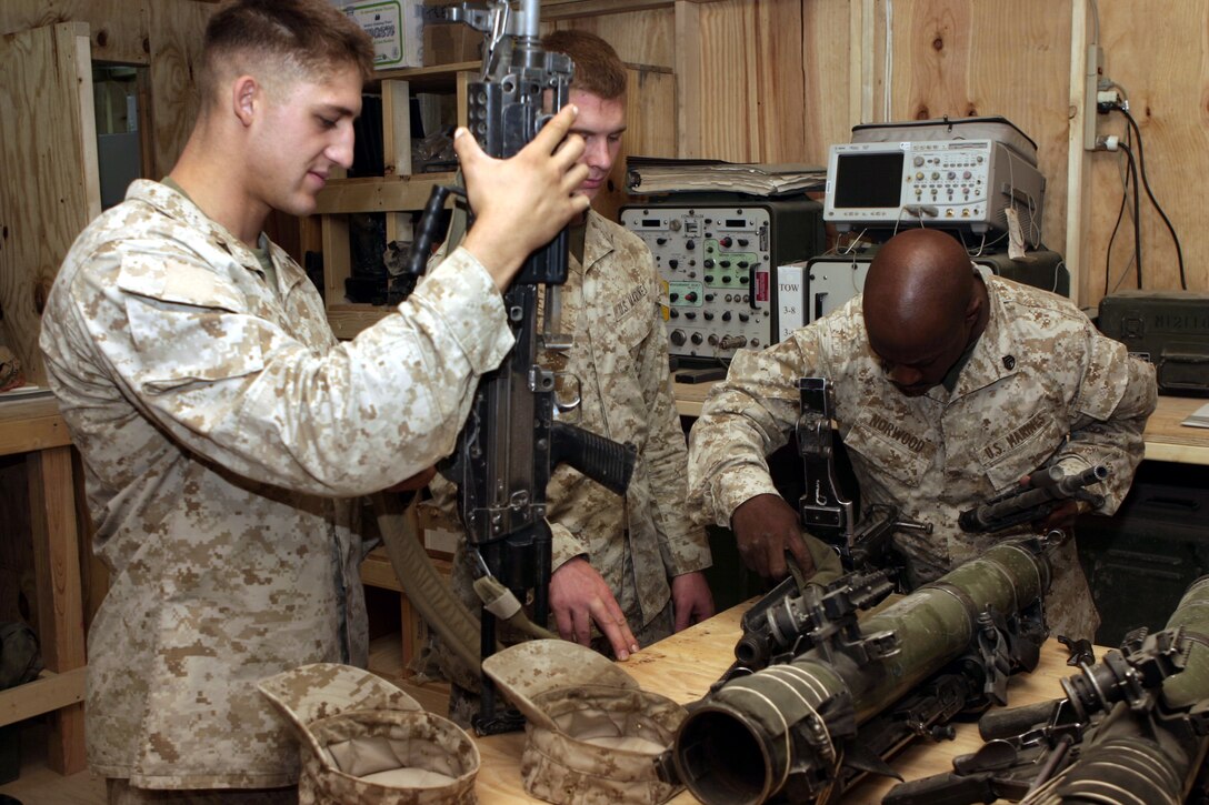 CAMP BAHARIA, Iraq - Staff Sgt. Kevin Norwood, 1st Battalion, 6th Marine Regiment's armory chief, right, inspects a Marines' malfunctioning M249 Squad Automatic Weapon here Aug. 9.  Every week, the battalion's small arms and optics technicians troubleshoot, inspect and repair more than 100 rifles, machineguns and night-vision units that infantrymen use while they patrol the streets of Fallujah.