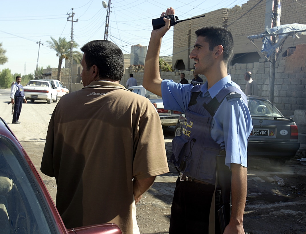 SAQLAWIYAH, Iraq - An Iraqi policeman waves to a citizen while patrolling through the streets here recently.  Saqlawiyah had no police force until several months ago, when U.S. Marines helped facilitate their entry back into the city.  Currently, the policemen patrol the rural township's streets to maintain civil order and acquaint themselves with the citizens, as Marines continue to train them on community policing and public relations skills.
