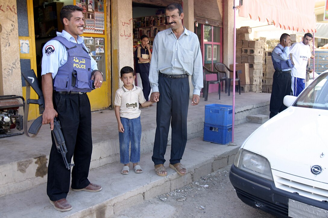 SAQLAWIYAH, Iraq - An Iraqi policeman interacts with a citizen while patrolling through the streets here recently.  Saqlawiyah had no police force until several months ago, when U.S. Marines helped facilitate their entry back into the city.  Currently, the policemen patrol the rural township's streets to maintain civil order and acquaint themselves with the citizens, as Marines continue to train them on community policing and public relations skills.