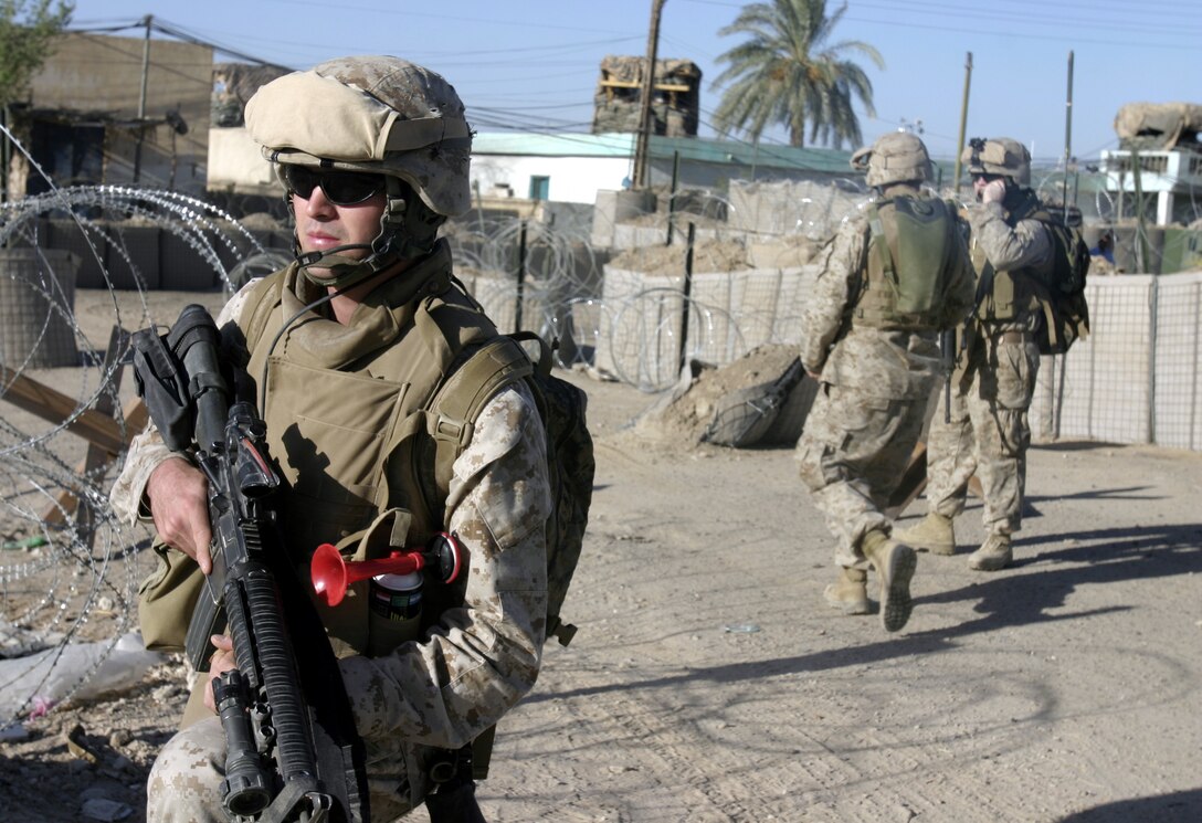 SAQLAWIYAH, Iraq - Corporal Daniel McNeill, a mortar man with Company A, 1st Battalion, 6th Marine Regiment, provides security outside Saqlawiyah's police station while his patrol passes by.  Saqlawiyah had no police force until several months ago, when U.S. Marines helped facilitate their entry back into the city.  Currently, the policemen patrol the rural township's streets to maintain civil order and acquaint themselves with the citizens, as Marines continue to train them on community policing and public relations skills.