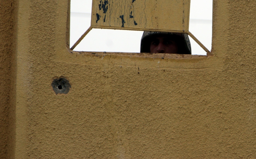 AR RAMADI, Iraq (November 16, 2005) - An Iraqi soldier from the local Iraqi Army peers through a window during a patrol through Ar Ramadi Nov. 16. The patrol was one of the first joint patrols to be planned and executed almost entirely by the IA. Photo by Cpl. Shane Suzuki