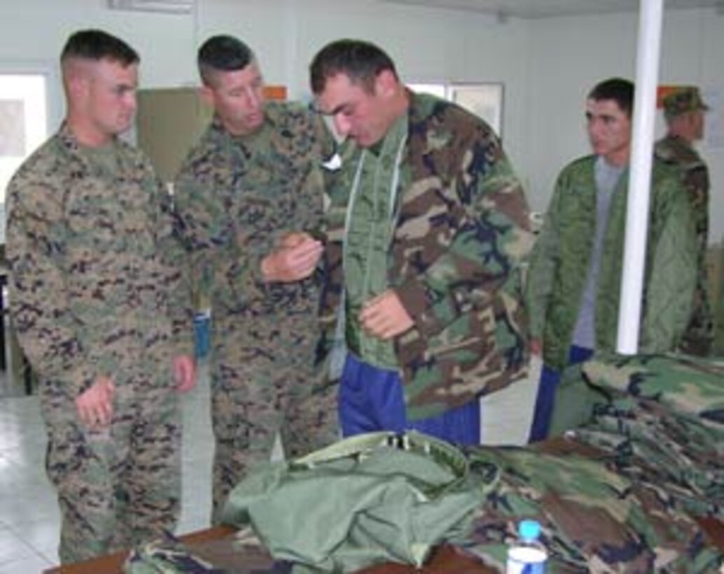 1st Lt. Colin Flynn, the Georgia Sustainment and Stability Operations Program Team officer in charge for the 22nd Battalion's Charlie Company and Gunnery Sgt. David Harris, the GSSOP logistics chief check the fit of a camouflage utility blouse on a Georgian soldier at Krtsanisi Training Area, Sept. 9, 2005. The gear has been permanently issued as a donation to the 22nd Battalion under parameters the GSSOP mission, which is to assist and enhance Georgia?s military capability to sustain its contribution to the effort in Iraq.
