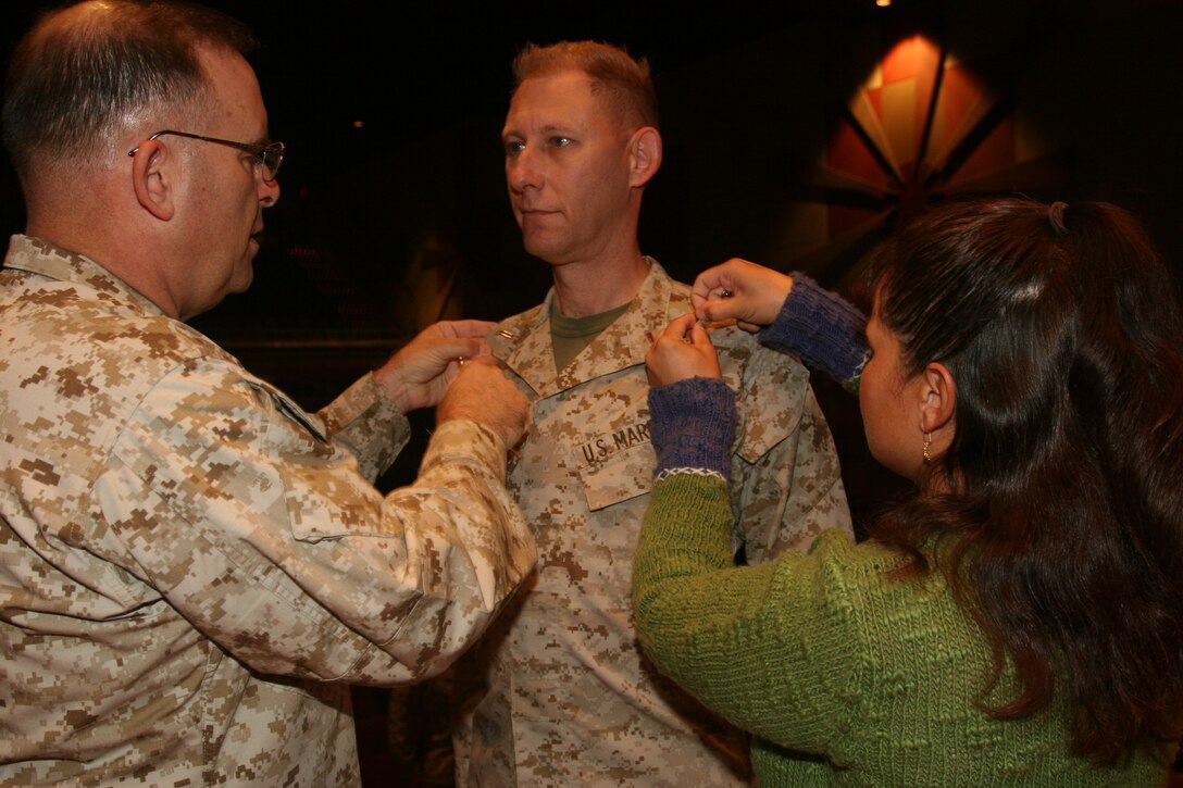 Chief Warrant Officer 5 Robert C. Jacob III, Marine Corps Air Ground Combat Center Band officer, gets promoted by his wife, Anne, and Brig. Gen. Douglas M. Stone, Combat Center commanding general, Dec. 9 at the base theater.  Jacob will go on to Headquarters Marine Corps to be the head of the Marine Corps music field.