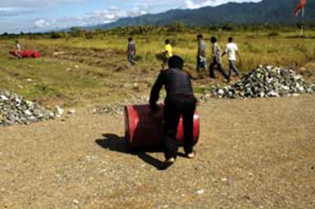 A local resident rolls an empty drum toward a CH-53E Super Stallion helicopter while it pumps desperately needed fuel for grounded Indonesian pilots supporting the humanitarian effort. The 15th Marine Expeditionary Unit (Special Operations Capable) has been providing desperately needed humanitarian aid to cities and villages along more than 150 miles of Sumatra's western coastline.