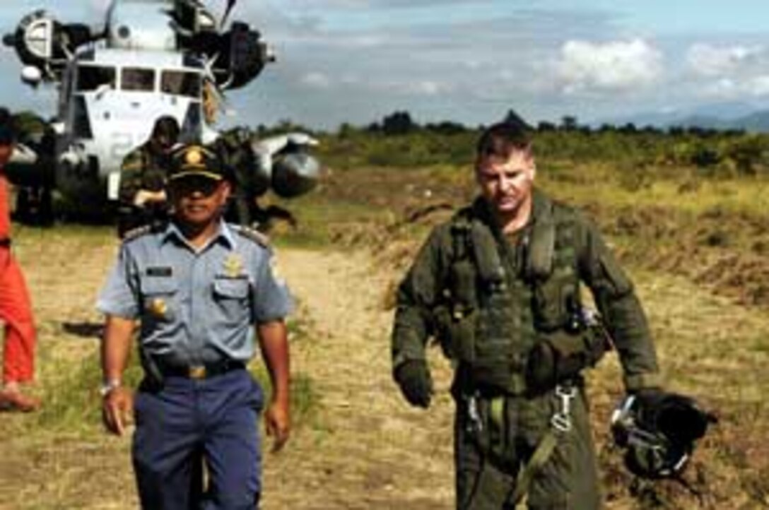 Trikoria, an Indonesian government representative, left, walks with Maj. Ron Carson, 38, a CH-53E pilot with Marine Medium Helicopter Squadron 165 (REIN) to discuss a humanitarian fuel delivery. The 15th Marine Expeditionary Unit (Special Operations Capable) has been providing desperately needed humanitarian aid to cities and villages along more than 150 miles of Sumatra's western coastline.