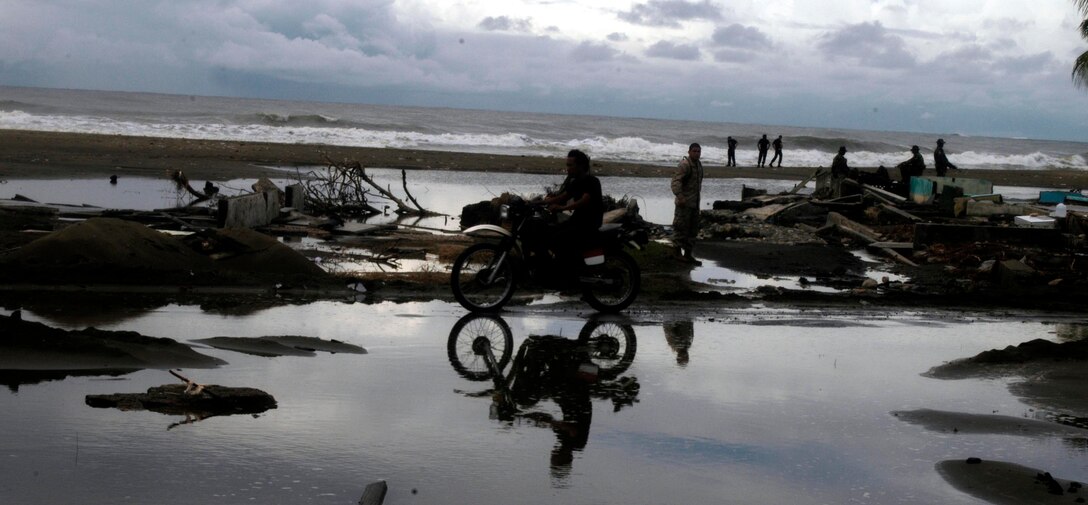 MEULABOH, Indonesia (Jan. 10, 2005) -- An Indonesian motorcycle rider drives across a piece of land not flooded in the aftermath of the Dec. 26 Tsunami.  15th Marine Expeditionary Unit (Special Operations Capable) has been providing desperately needed humanitarian aid to cities and villages along more than 150 miles of Sumatra's western coastline.  (Photo by Gunnery Sgt. Robert Knoll)