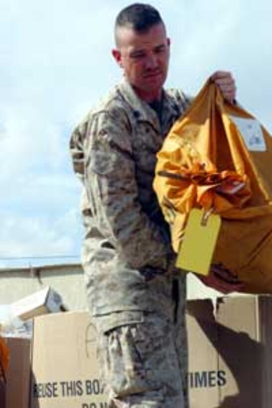 Sgt. Christopher Eskridge, 26, a postal clerk with the 15th Marine Expeditionary Unit (Special Operations Capable) and native of Ottawa, unloads a bag of mail at a Forward Operating Base here. Thousands of letters and packages have been received by 15th MEU Marines and Sailors since arriving in Iraq. The unit is currently conducting security and stability operations here in the greater Baghdad area.
